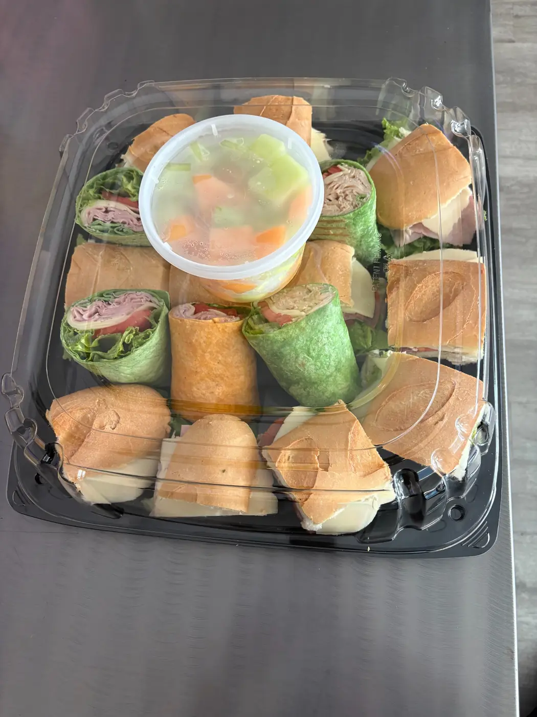 Dockside lunch catering platter with assorted sandwiches, wraps, and fresh fruit