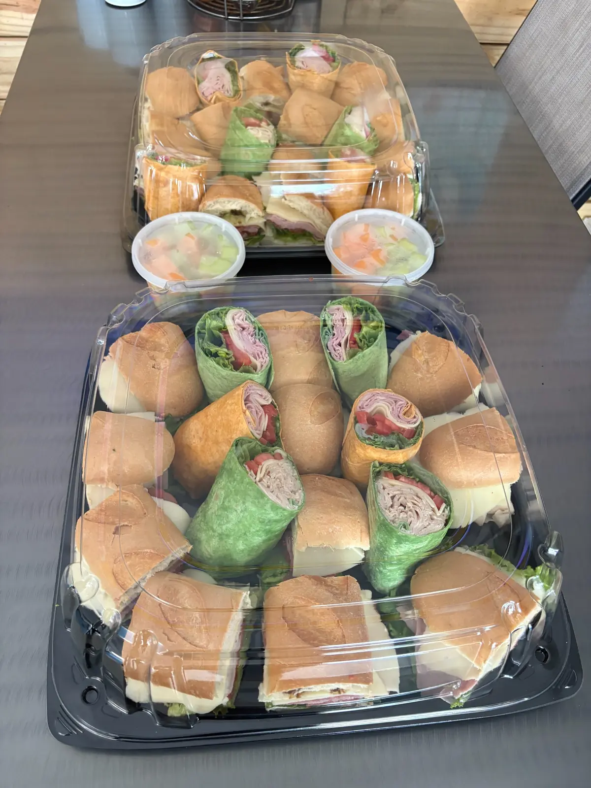 Two Dockside lunch catering platters with assorted sandwiches, wraps, and fresh fruit